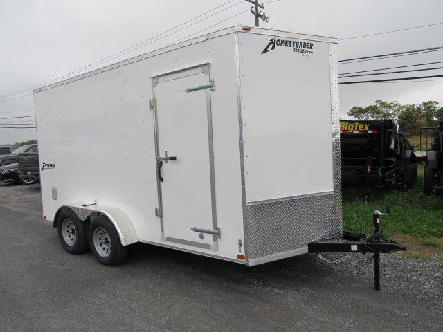 a white trailer is parked on the side of the road .