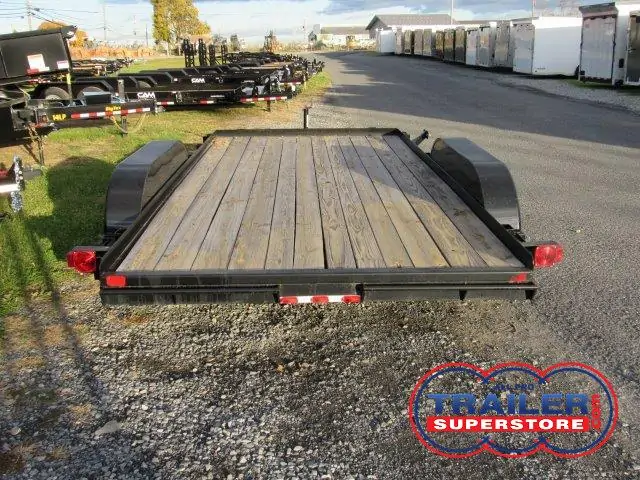 a trailer with a wooden deck is parked in a gravel lot