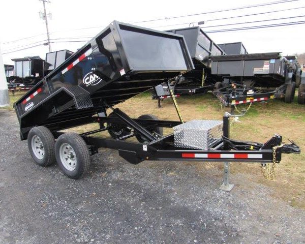 a dump trailer is sitting on top of a dirt field .
