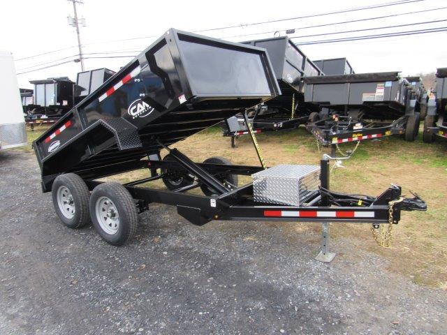 a dump trailer is sitting on top of a dirt field .