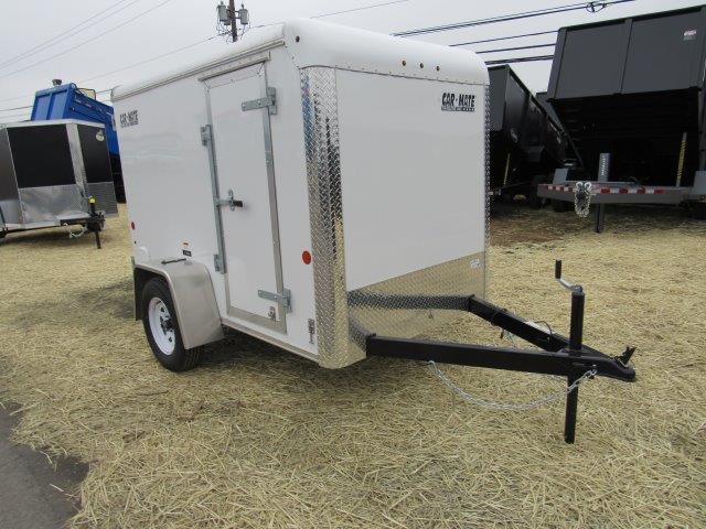 a white trailer is parked in a field of hay .