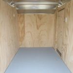 a small empty trailer with wooden walls and a gray floor .