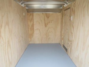 a small empty trailer with wooden walls and a gray floor .