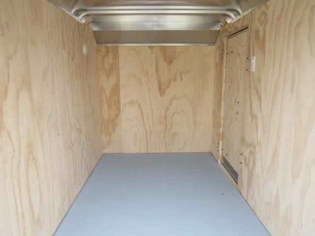 a small empty trailer with wooden walls and a gray floor .