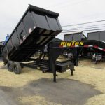 a big tex dump trailer is sitting on top of a dirt field .