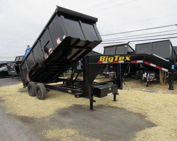 a big tex dump trailer is sitting on top of a dirt field .