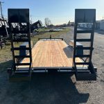 a trailer with a wooden deck is parked in a parking lot .