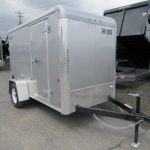 a silver trailer is parked in a parking lot next to a dump trailer