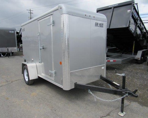 a silver trailer is parked in a parking lot next to a dump trailer