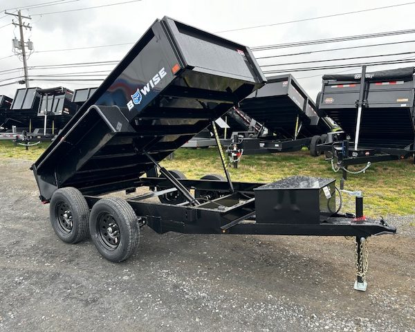 a bwise dump trailer is parked in a gravel lot