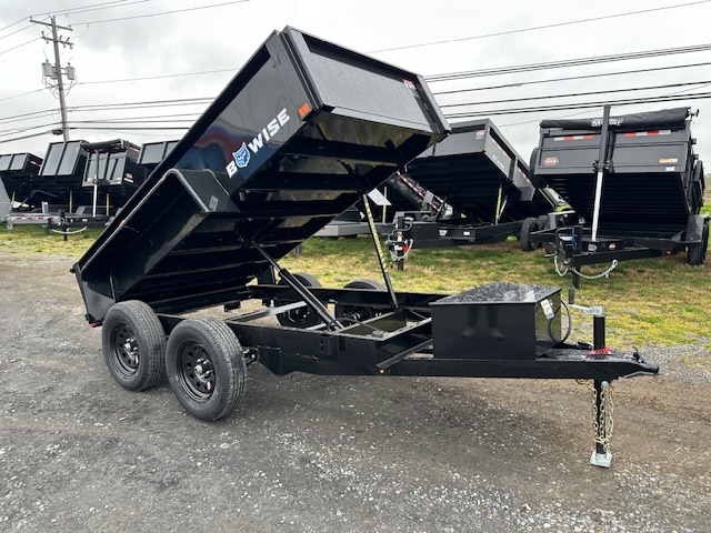 a bwise dump trailer is parked in a gravel lot