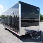 a black and silver trailer parked in a gravel lot