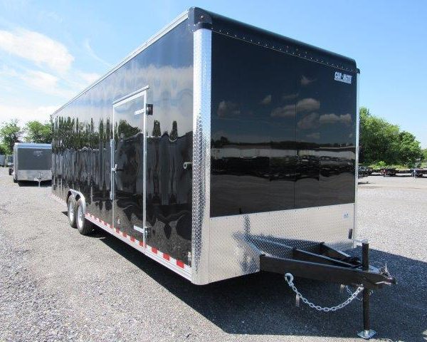 a black and silver trailer parked in a gravel lot