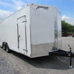 a white trailer parked in a gravel lot