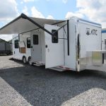 a white trailer with an awning parked in a gravel lot