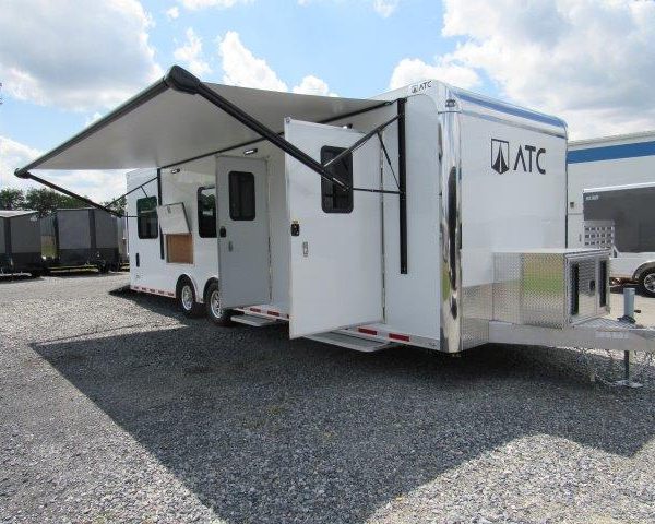 a white trailer with an awning parked in a gravel lot