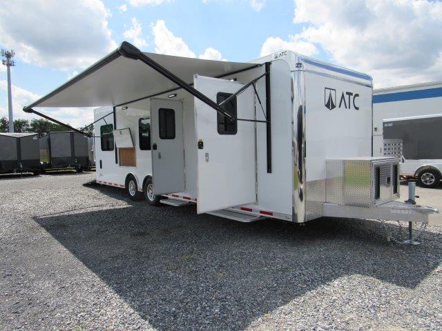 a white trailer with an awning parked in a gravel lot
