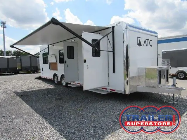 a white trailer with an awning parked in a gravel lot