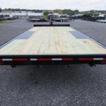 a premier flatbed trailer with a wooden deck is parked in a parking lot .