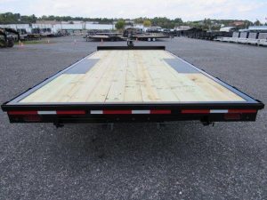 a premier flatbed trailer with a wooden deck is parked in a parking lot .