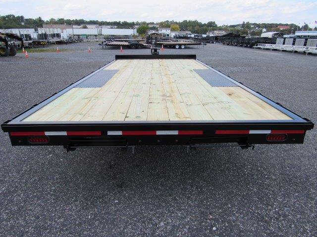a premier flatbed trailer with a wooden deck is parked in a parking lot .