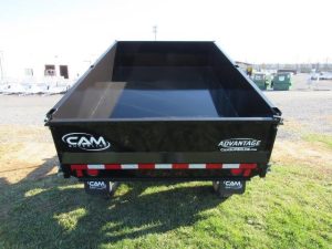 a cam dump trailer is sitting on top of a lush green field .