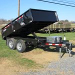 a CAM Superline deckover dump trailer parked in a grassy field