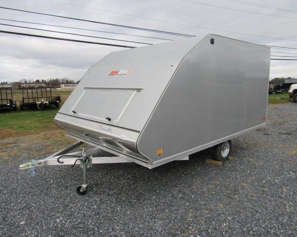 a silver trailer is parked in a gravel lot .