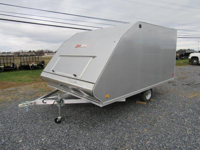 a silver trailer is parked in a gravel lot .