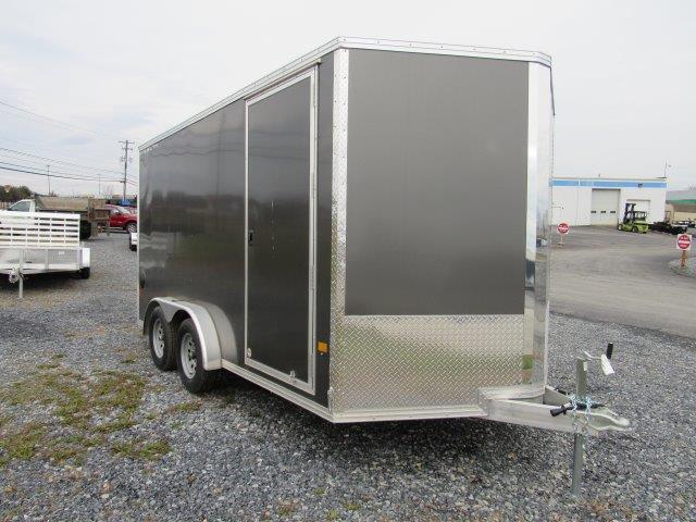 a black and silver trailer is parked in a gravel lot .