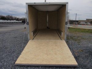 a trailer with the door open is sitting in a gravel lot .