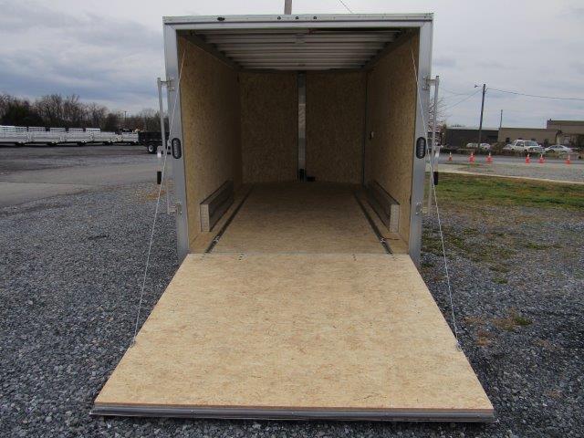 a trailer with the door open is sitting in a gravel lot .