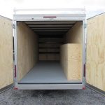 the inside of a car mate trailer with the doors open .