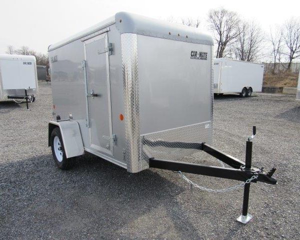 a silver trailer is parked in a gravel lot