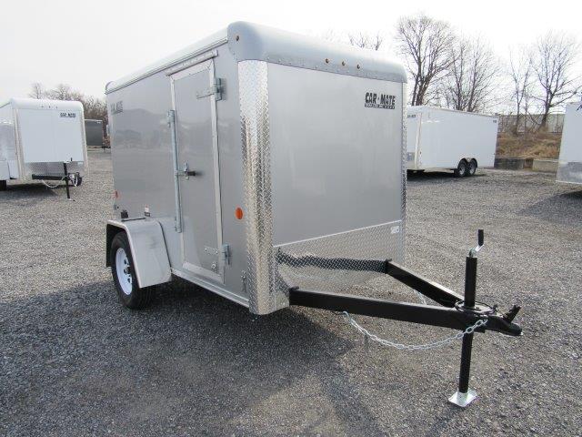 a silver trailer is parked in a gravel lot