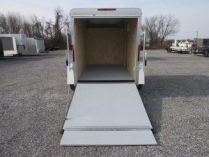 a white trailer with the door open is parked in a gravel lot