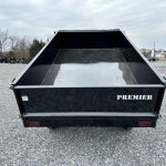 a black dump trailer parked in a gravel lot