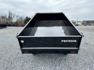a black dump trailer parked in a gravel lot