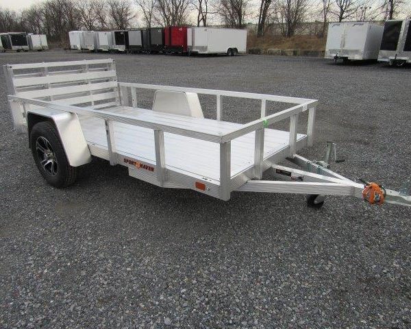 a small aluminum trailer is parked in a gravel lot