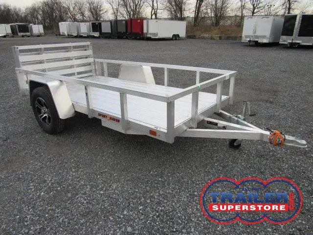 a small aluminum trailer is parked in a gravel lot