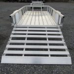 a Sport Haven trailer with a ramp attached to it parked in a gravel lot