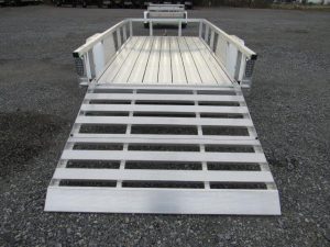 a Sport Haven trailer with a ramp attached to it parked in a gravel lot