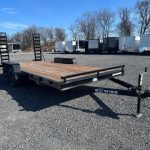 a Bwise trailer with a wooden deck parked in a gravel lot