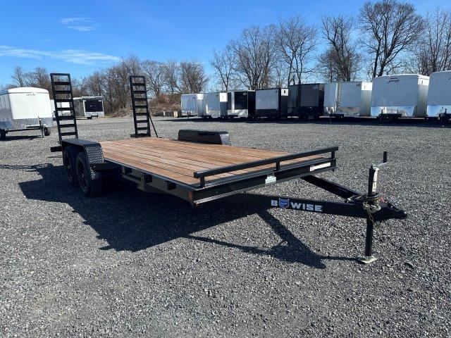 a Bwise trailer with a wooden deck parked in a gravel lot