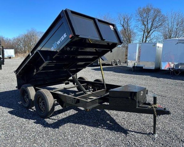 a black dump trailer parked in a gravel lot