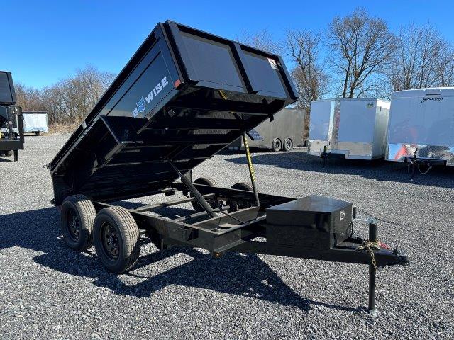 a black dump trailer parked in a gravel lot