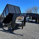 a black dump trailer is parked on a gravel lot