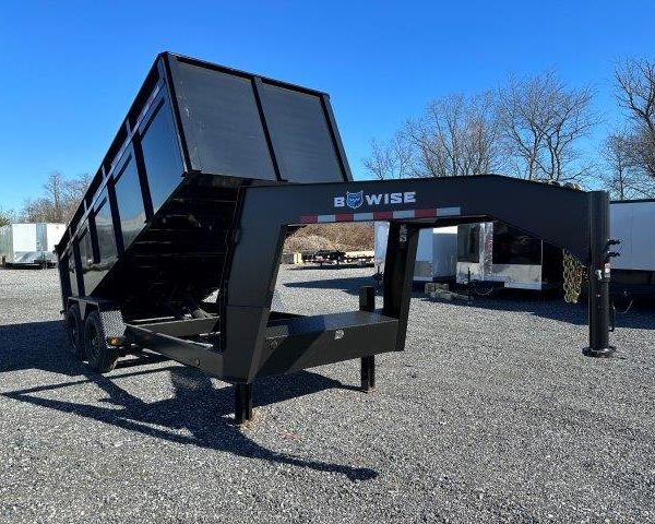 a black dump trailer is parked on a gravel lot