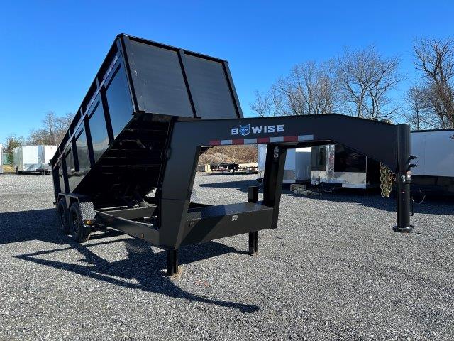 a black dump trailer is parked on a gravel lot