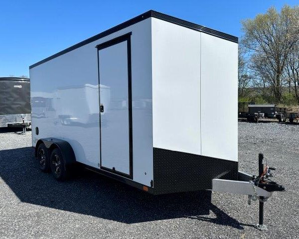 a white and black trailer is parked in a gravel lot